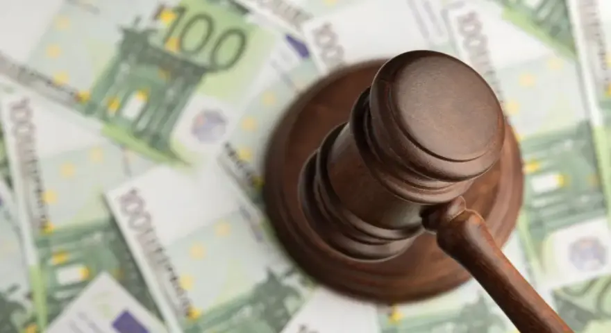 Młotek sędziowski na tle banknotów 100 euro.