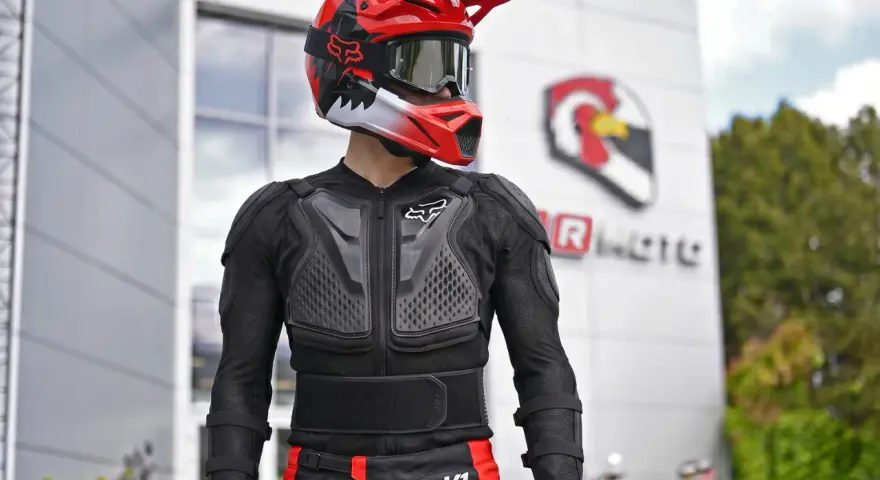 Motocyklista w kasku i ochraniaczach. Kurtka z membraną chroni przed wiatrem i deszczem, zapewniając komfort.