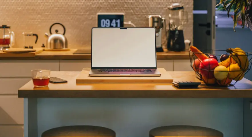 Ein Laptop steht auf einer Küchentheke neben Obst und einem Glas Tee. Vielleicht fragst du dich, was Bixby ist – ein digitaler Assistent, der dir bei vielen Dingen helfen kann.