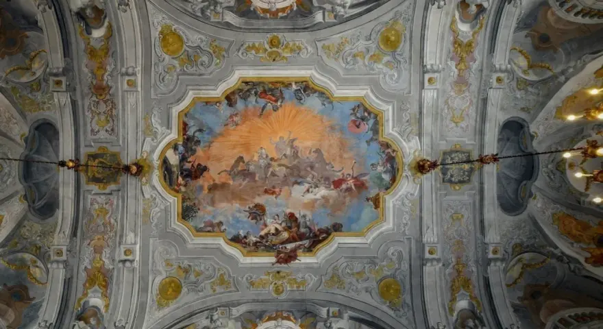 Plafond orné de fresques célestes, un exemple de style **rococo def.**, avec des anges, des chevaux et un soleil éclatant.