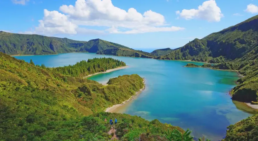 Lago blu circondato da colline verdi lussureggianti, con piccole isole e una spiaggia sabbiosa. Perfetto per capire quando andare alle Azzorre.