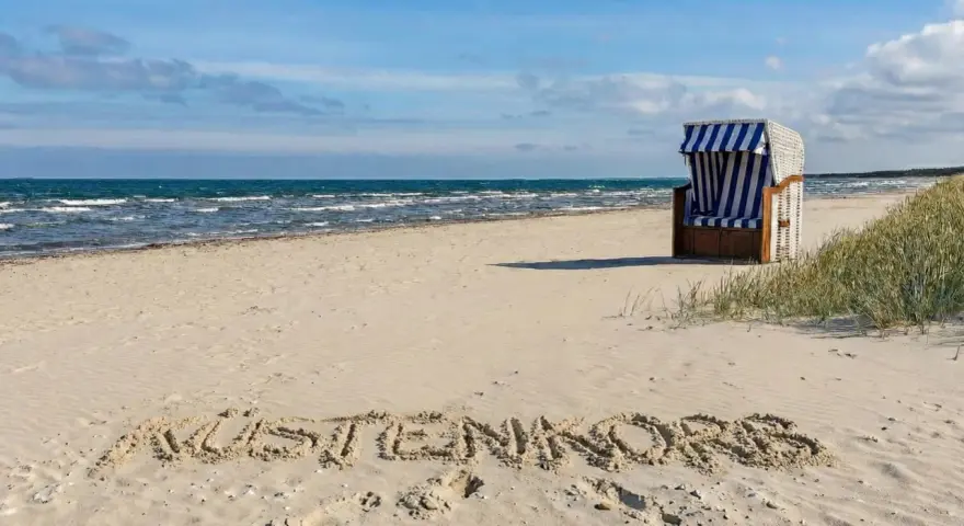 Der Juliusruh Strand lädt mit einer Strandmuschel und dem Schriftzug "KUSTENKORS" im Sand zum Verweilen ein.