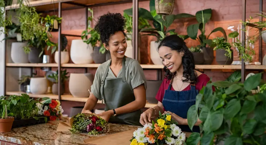 Deux fleuristes souriantes créent des bouquets. Un métier artistique bien payé qui embellit le quotidien.