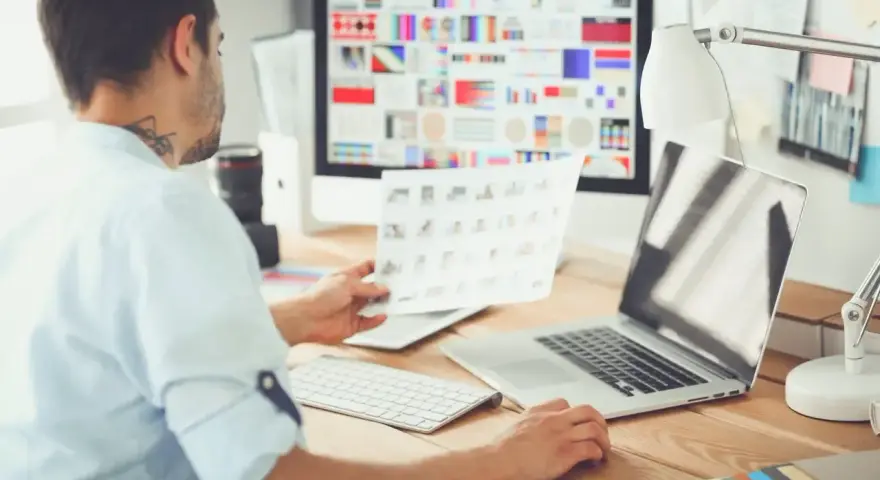 UX designer analizuje wydruki i ekran komputera z paletą barw.
