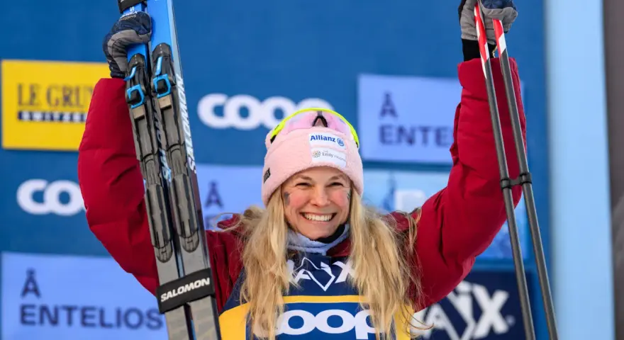 Uśmiechnięta narciarka z nartami w górze, świętuje sukces w biegach narciarskich. Klasyfikacja generalna FIS Cross Country World Cup.