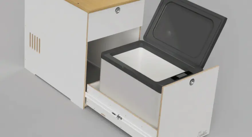 En kylbox med kompressor testas i en vit möbel med trädetaljer. Locket är öppet och lådan är utdragen.