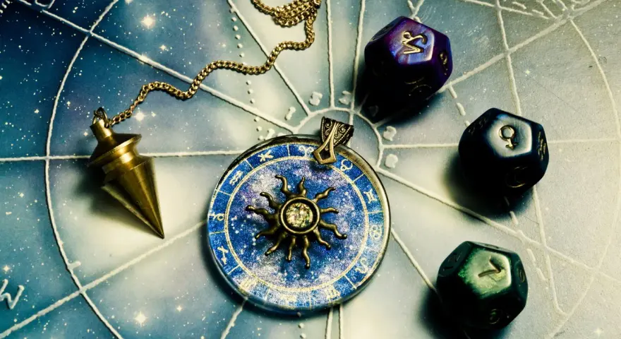 Wahadło i kostki do gry z symbolami zodiaku. Koziorożec jaki żywioł? Ziemia, symbol stabilności i determinacji.