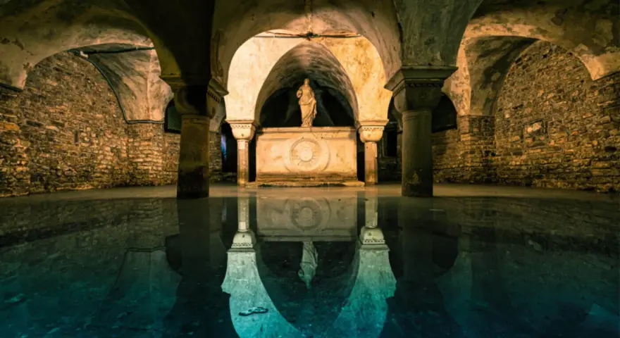 Un'antica cripta veneziana sommersa, con una statua su un altare e riflessi sull'acqua. Un tesoro nascosto di Venezia.