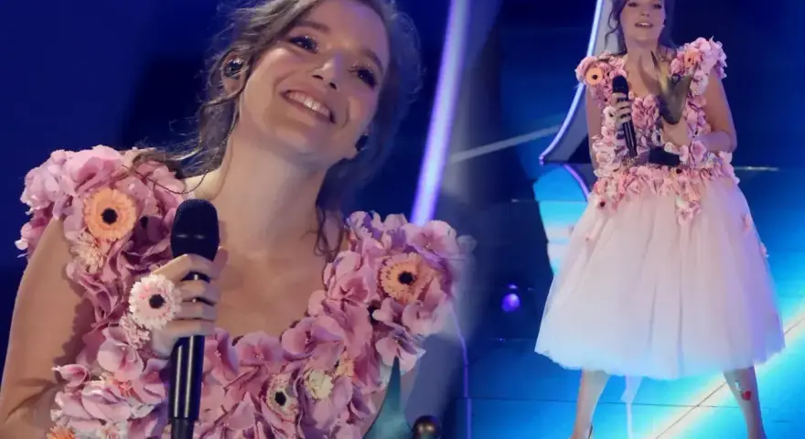 Zuzanna Jurczak, znana jako piosenkarka, w kwiecistej sukni na scenie.
