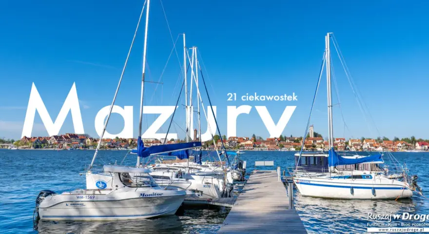 Żaglówki cumujące w porcie na Mazurach, Polska. W tle malownicze miasteczko nad jeziorem.
