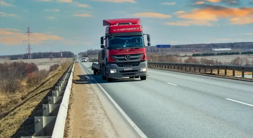 Czerwona ciężarówka jedzie autostradą. Ubezpieczenie kabotażowe zapewnia spokój podczas międzynarodowych transportów.
