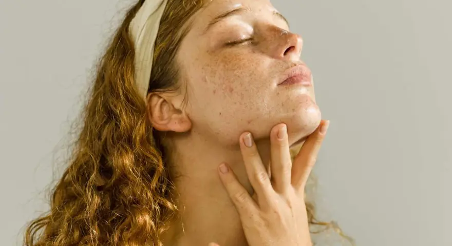 A young woman with freckles enjoys a relaxing skin care massage, her eyes closed in bliss.