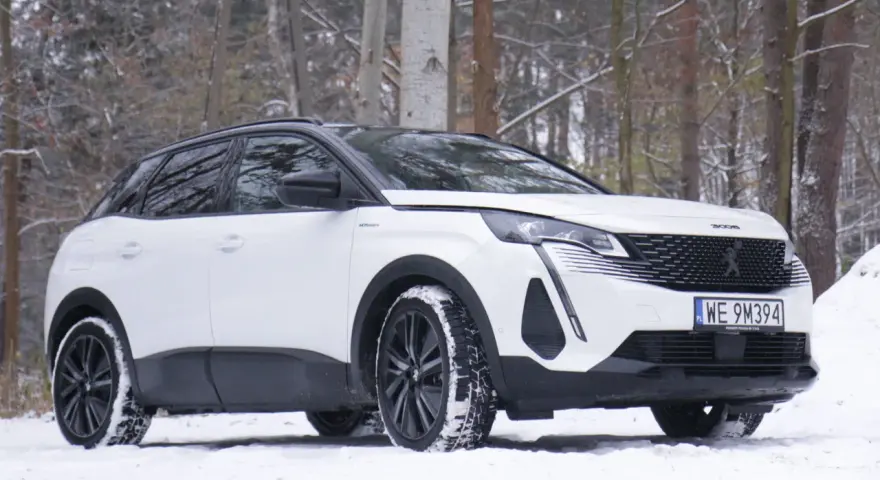 Biały Peugeot 3008 hybryda na śniegu, gotowy na zimowe przygody w lesie.