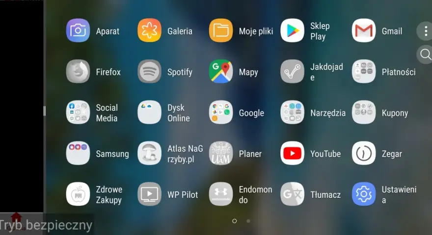 Ekran telefonu z ikonami aplikacji. Widoczny jest pasek "Tryb bezpieczny", co sugeruje, jak włączyć tryb awaryjny w telefonie.