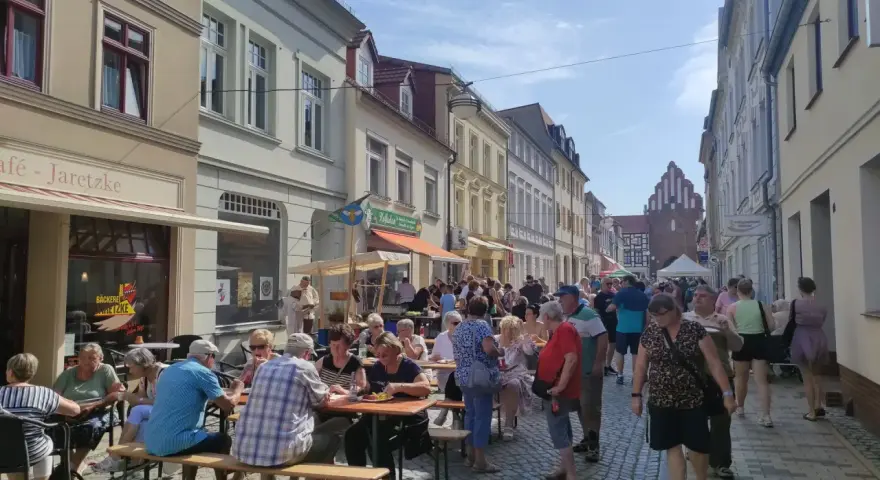 Menschen genießen ein Fest vor dem Kulturhaus Teterow. Viele sitzen an Tischen, essen und unterhalten sich.
