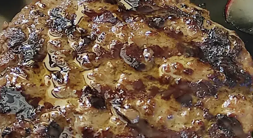 Hamburger in padella succulento, con crosticina dorata e succo che cola. Perfetto per un pasto veloce e gustoso.