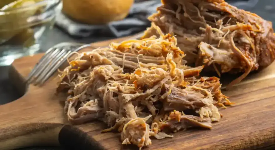 Un délicieux effiloché de porc, tendre et savoureux, prêt à être dégusté sur une planche en bois.
