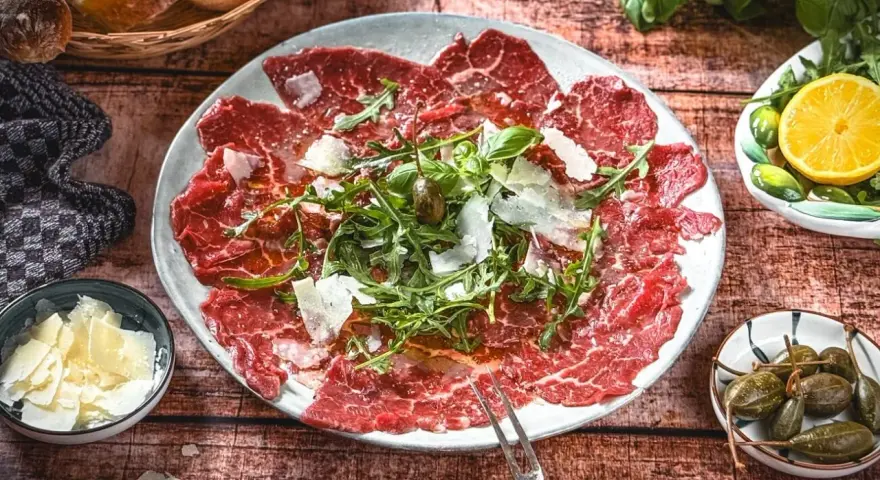Carpaccio: hauchdünne Rindfleischscheiben mit Rucola, Parmesan und Kapern. Ein Klassiker der italienischen Küche.
