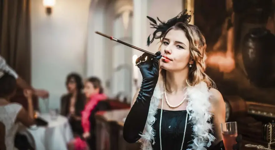 Kobieta w stylu lat 20. z cygaretką i piórami, na tle imprezy.