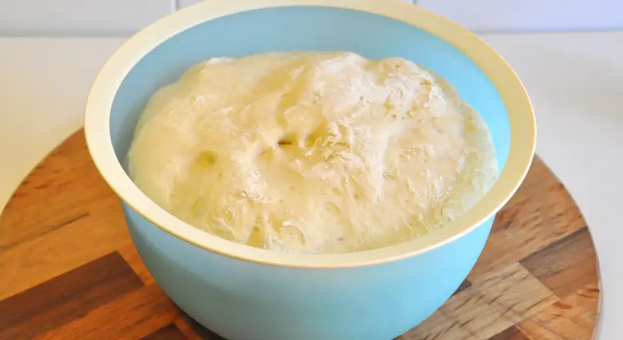 Impasto pizza bimby lievitato in una ciotola azzurra, pronto per essere steso.