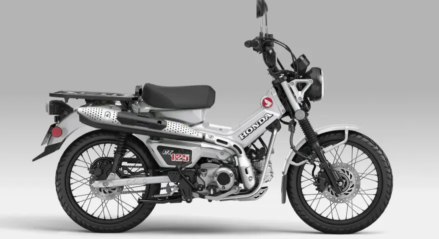 Srebrny motocykl Honda CT 125 z czarnym siedzeniem i bagażnikiem, gotowy na przygodę.