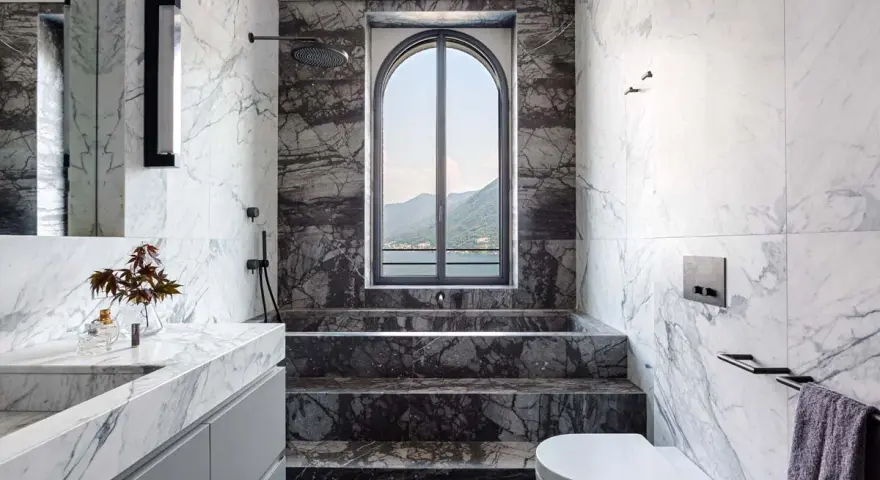 Bagno di lusso con vasca doccia in muratura, rivestimenti in marmo e vista panoramica.