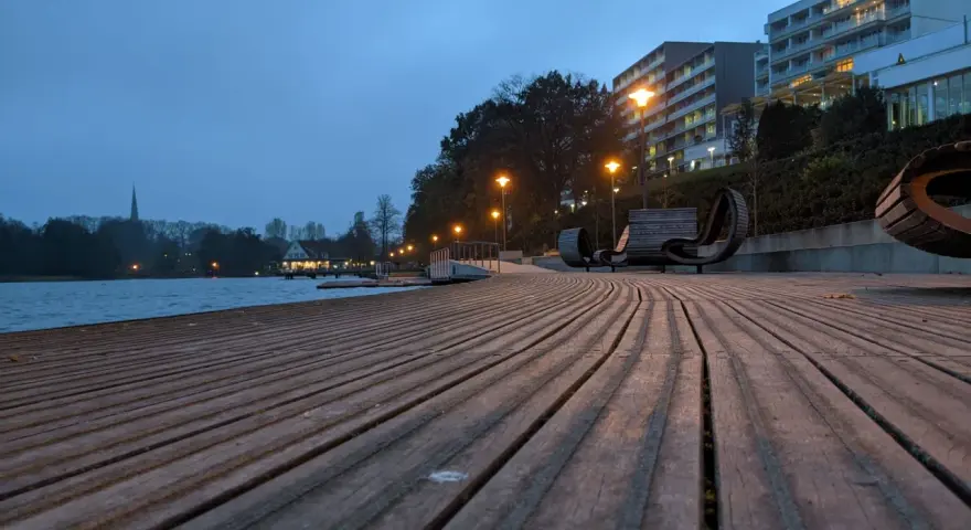 Holzdeck am See mit modernen Bänken und Beleuchtung. Ein schöner Ort für **Bad Segeberg Unternehmungen** am Abend.