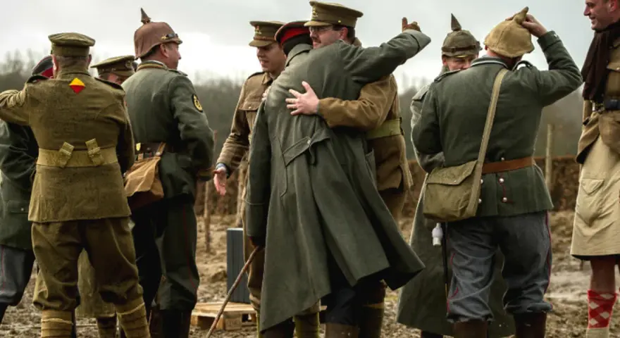 Des soldats en uniforme s'embrassent, une scène évoquant la trêve de Noël 1914.