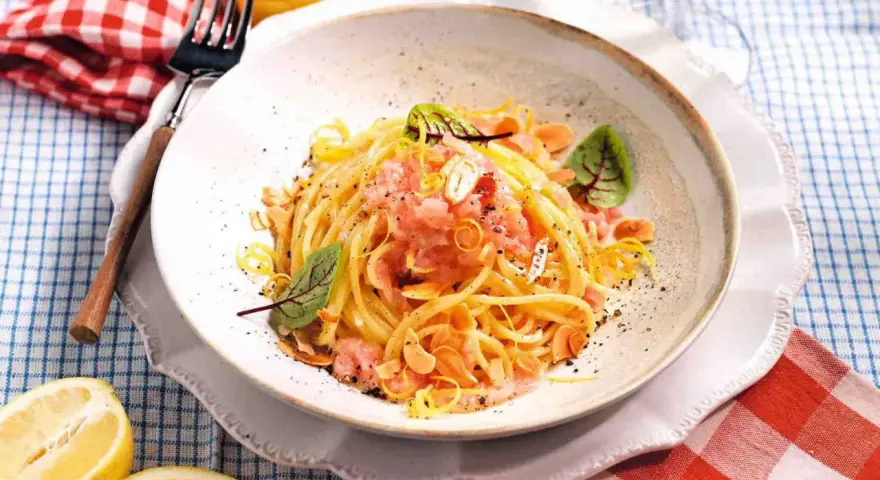Spaghetti con sughi in bianco, conditi con limone, mandorle e un tocco di rosa.