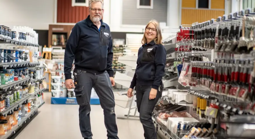 Två anställda står i en butik med färg och verktyg. De hjälper dig gärna att välja rätt färg för att måla fasad.