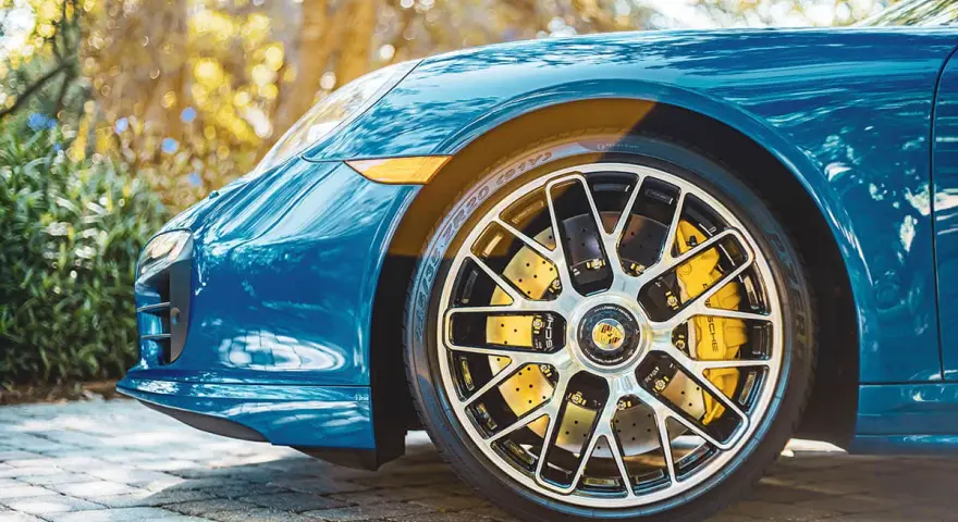 Błękitne Porsche z żółtymi zaciskami hamulcowymi i wieloramiennymi felgami. To jest et felgi, które dodają sportowego charakteru.