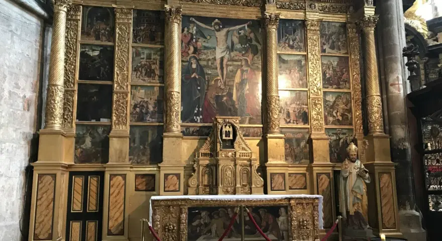 The ornate altar of the Basilica of Mary Magdalene features a central crucifixion scene surrounded by smaller narrative paintings, all set within a gilded structure.