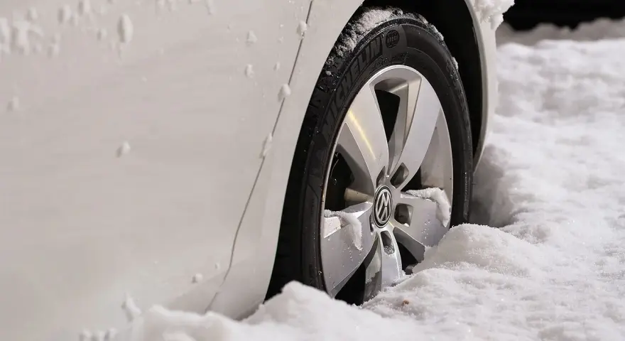 Białe auto w śniegu, widoczna felga z logo VW. Zastanawiasz się, jak zmierzyć rozstaw śrub?