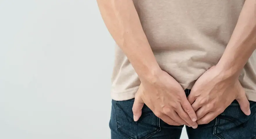 Osoba trzymająca się za pośladki, sugerująca problem z krwią z odbytu. Jaki lekarz może pomóc?