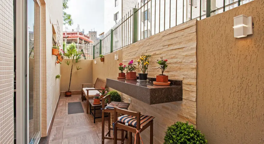Un balcón acogedor con muebles de madera, plantas y un estante de granito. Ideal para disfrutar de pequeños patios.