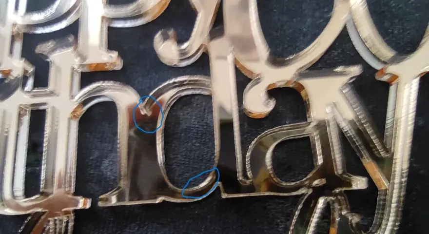 Close-up of a "Happy Birthday" acrylic mirror cake topper, showing the delicate edges and some minor imperfections from how to cut acrylic mirror.