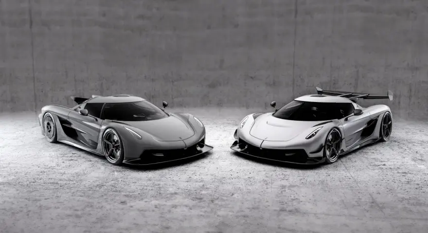 Dwa lśniące Koenigsegg Jesko, jeden szary, drugi srebrny, stoją obok siebie na betonowym tle, gotowe do wyścigu.