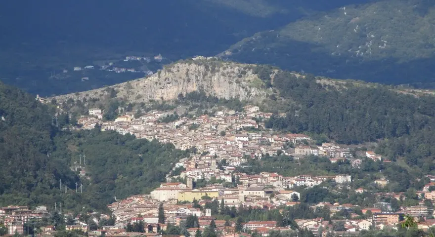 Borgo abruzzese arroccato su un colle, tra boschi e montagne. Immagina il **cammino dei briganti Abruzzo** che attraversa questi sentieri selvaggi.
