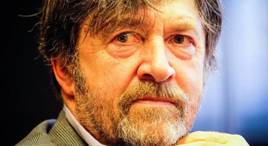 Zbliżenie na twarz Olek Krupa, z siwiejącą brodą i zmarszczkami wokół oczu.