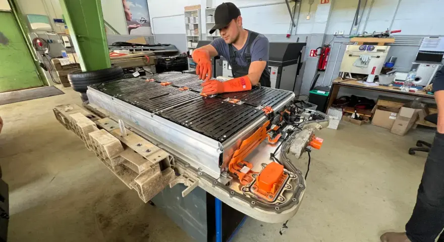 Mechaniker arbeitet an einer großen Batterieeinheit, die für Elektroautos bestimmt ist. Dies ist wichtig für die **Autobatterie Garantie**.