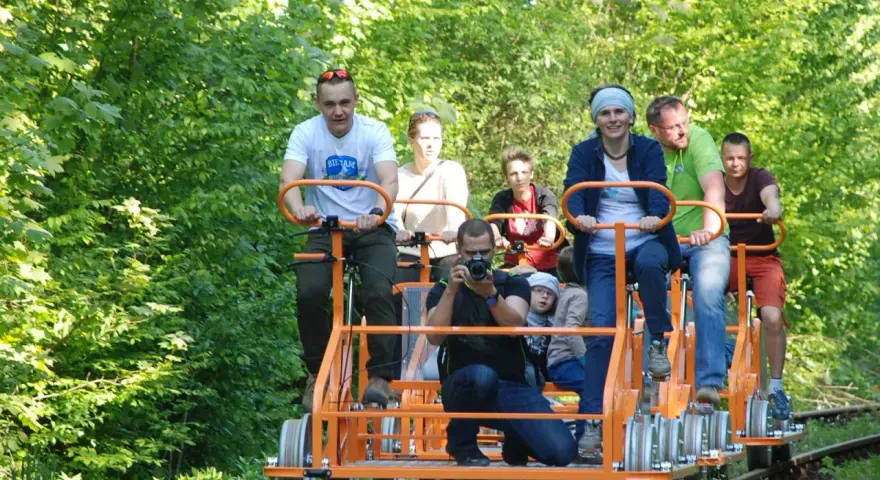 Rodzina na drezynach w Bieszczadach, ciesząca się zielenią i słońcem. Radość i wspólna przygoda na torach.
