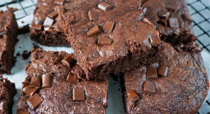 Saftige Zucchini Brownies mit Schokostückchen, die auf einem Gitterrost liegen.