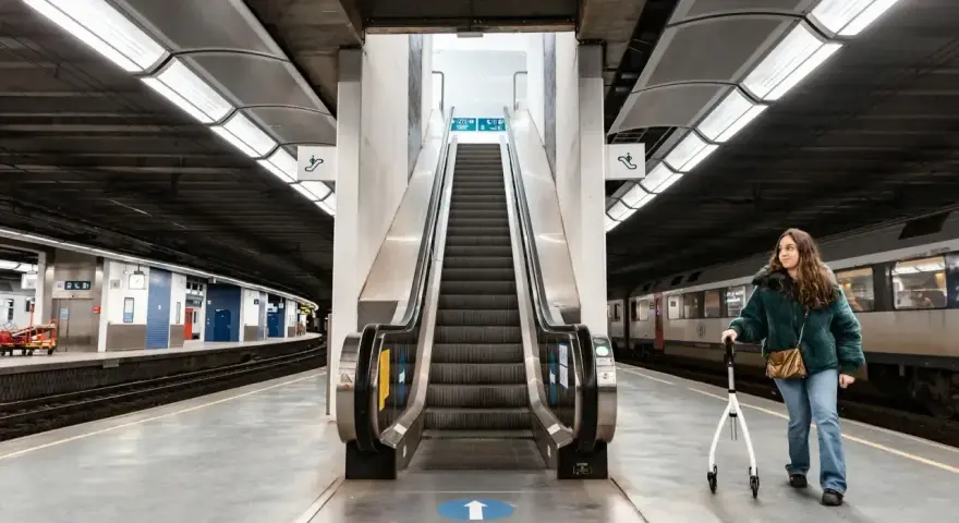 Kobieta z chodzikiem na dworcu kolejowym, gotowa na podróż pociągiem za granicę.