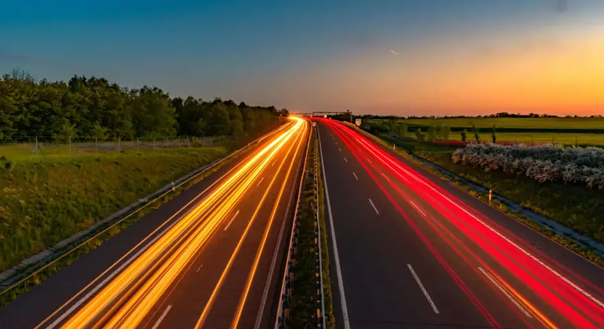 Ljusspår av bilar på en tysk autobahn vid solnedgången.