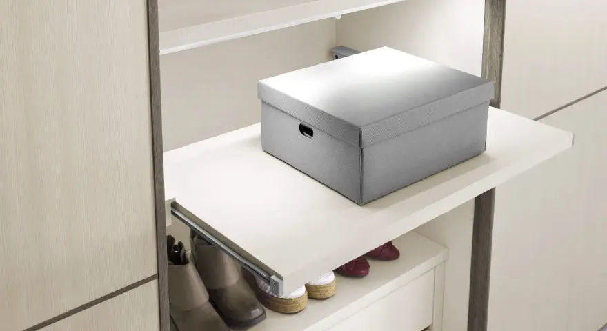 Un ripiano estraibile fai da te, con una scatola grigia sopra e scarpe sotto, ottimizza lo spazio in un armadio moderno.