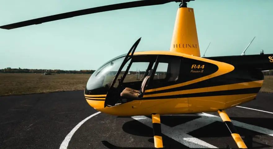 Żółto-czarny helikopter Robinson R44 Raven II na płycie lotniska. Marzysz, jak zostać pilotem helikoptera?