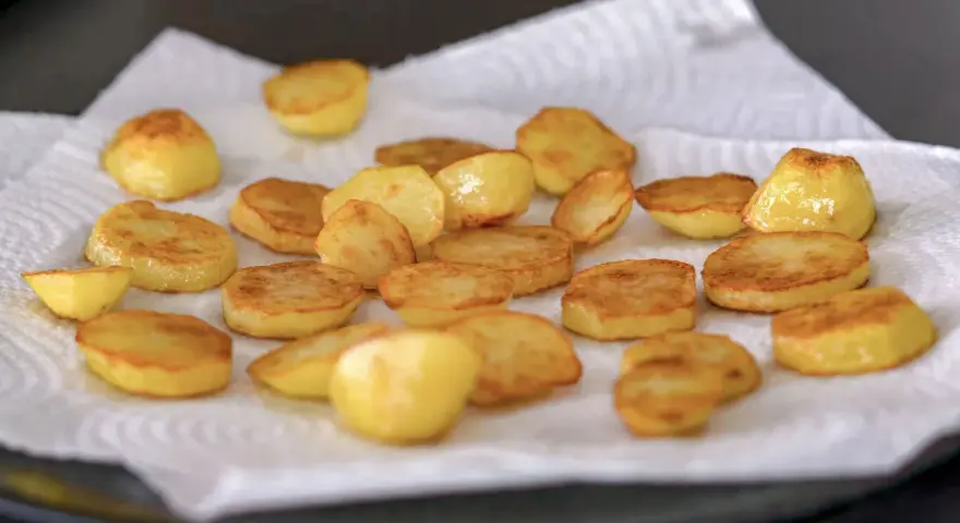 Patatas al horno doradas y crujientes, recién salidas del horno y reposando sobre papel absorbente. ¡Un manjar listo para disfrutar!