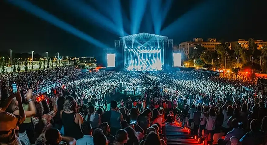 Multitud en un concierto nocturno, luces azules iluminan el escenario y al público. Un evento vibrante, como un **cabaret mairena** moderno.