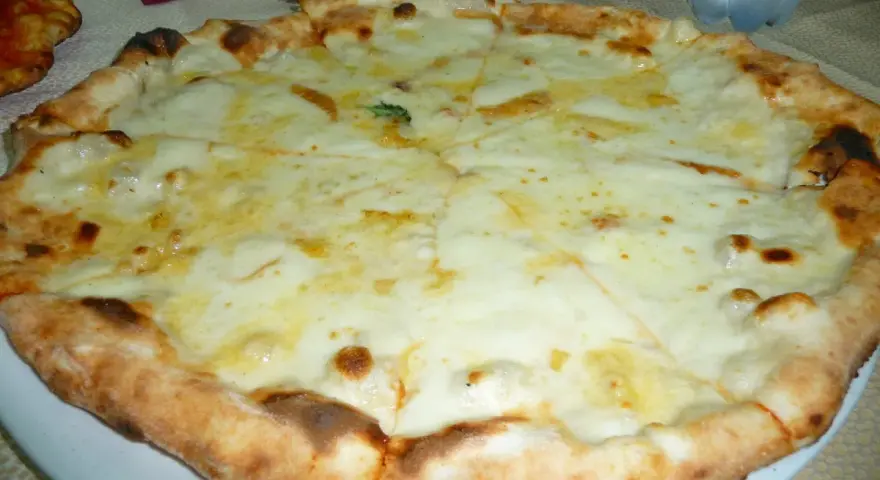 Pizza 4 formaggi appena sfornata, con crosta dorata e abbondante formaggio fuso.