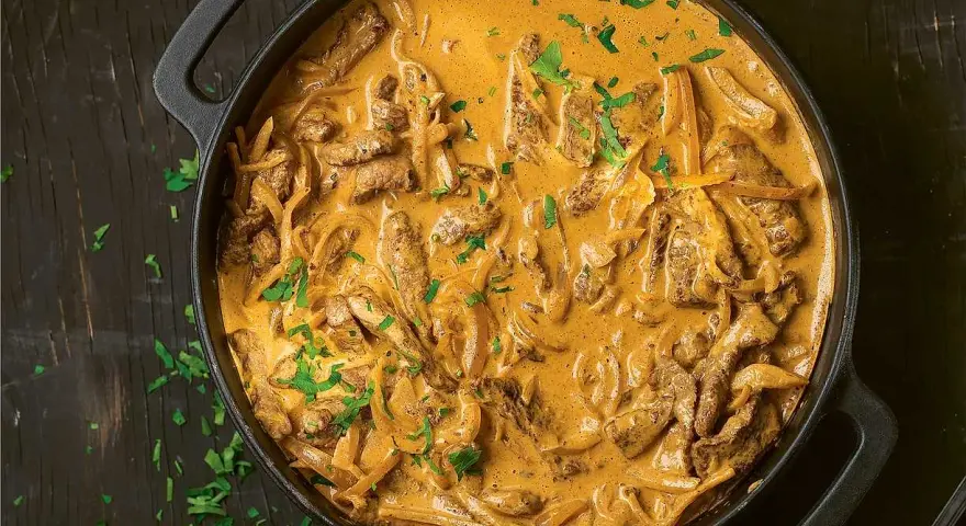 En gryta med krämig biff stroganoff, perfekt för ett mysigt middagsrecept. Garnerad med färsk persilja.